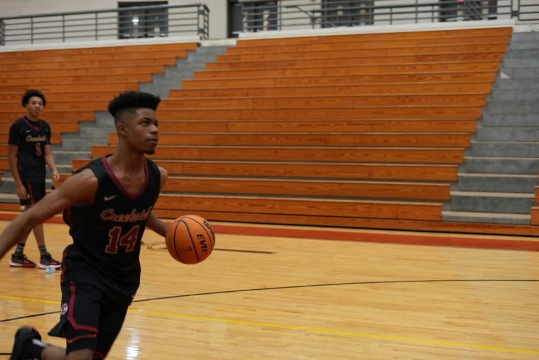 a young man holding a basketball while standing on a basketball court