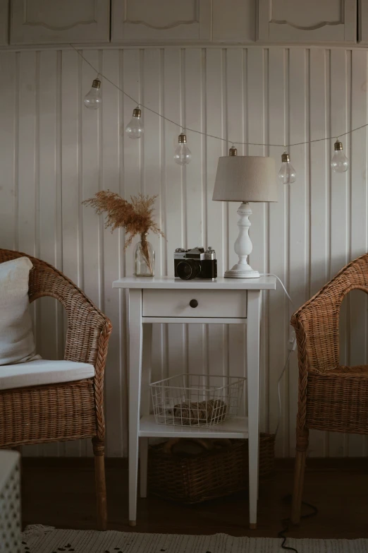 a wicker chair sitting next to a table with lamps and a lamp