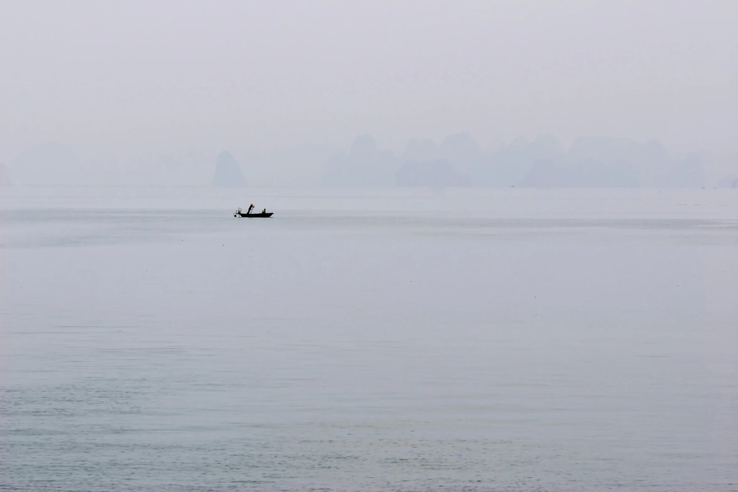 a lone boat sailing in calm waters on a foggy day