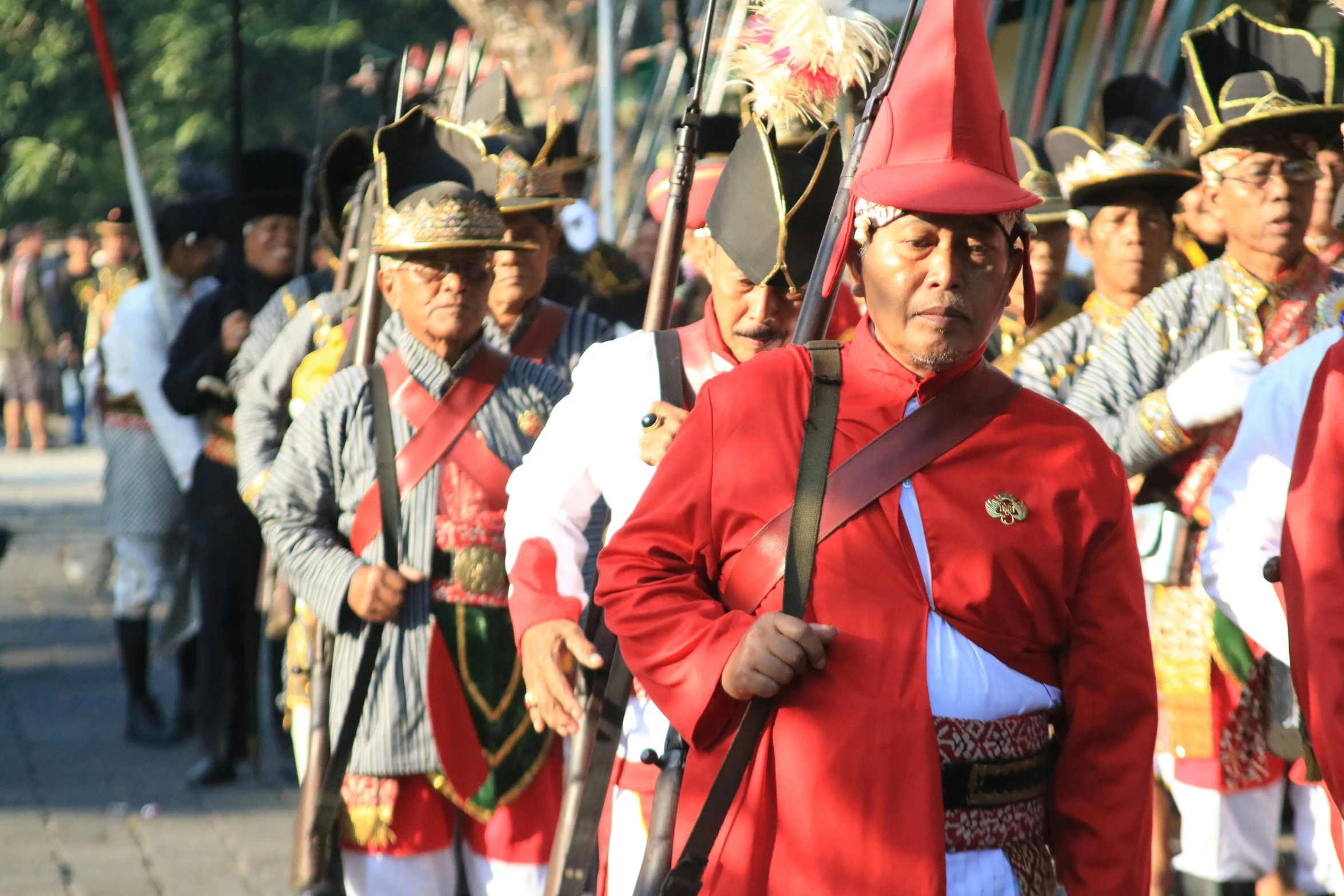 a parade of men in costume with red hats and uniforms