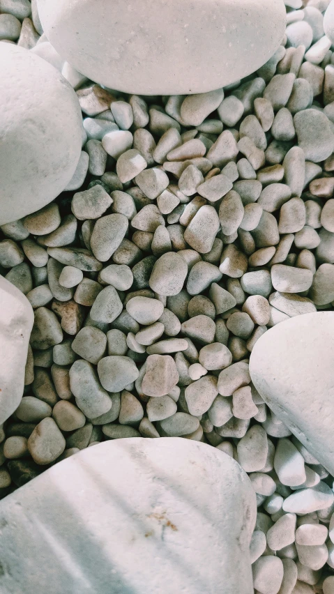 two white rocks sitting next to a pile of pebbles