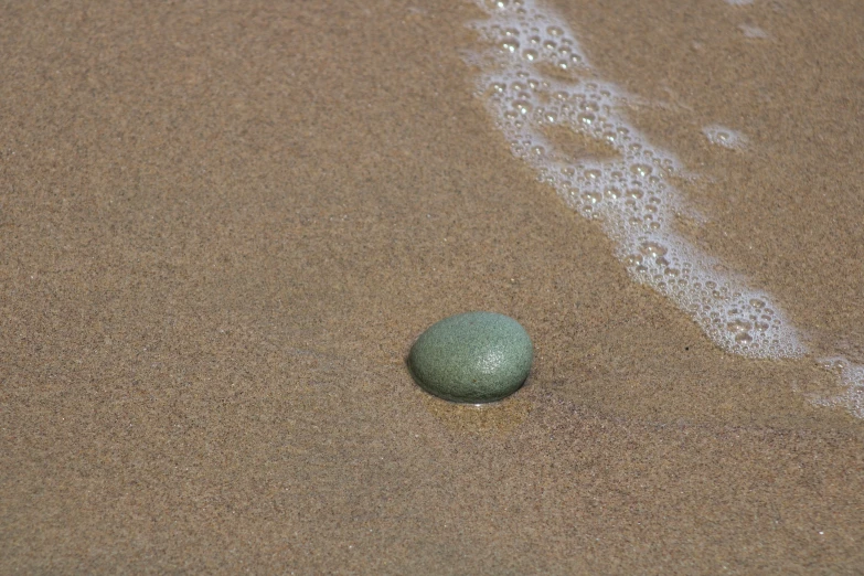 a single green ball on the sandy beach