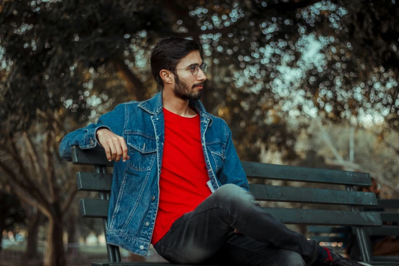 a man sitting on a park bench in a red shirt