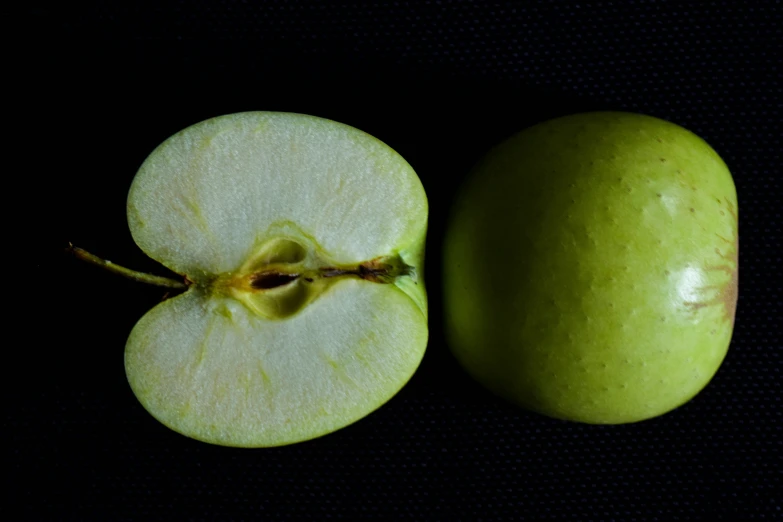 two pieces of green fruit with one cut in half