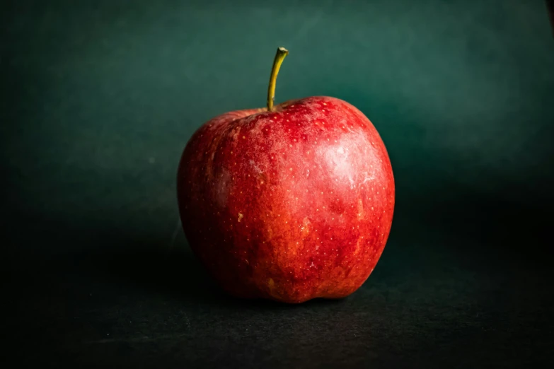 an apple sits in front of a dark background