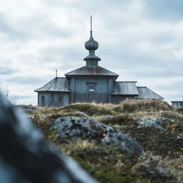 an old building on top of a hill near some rocks