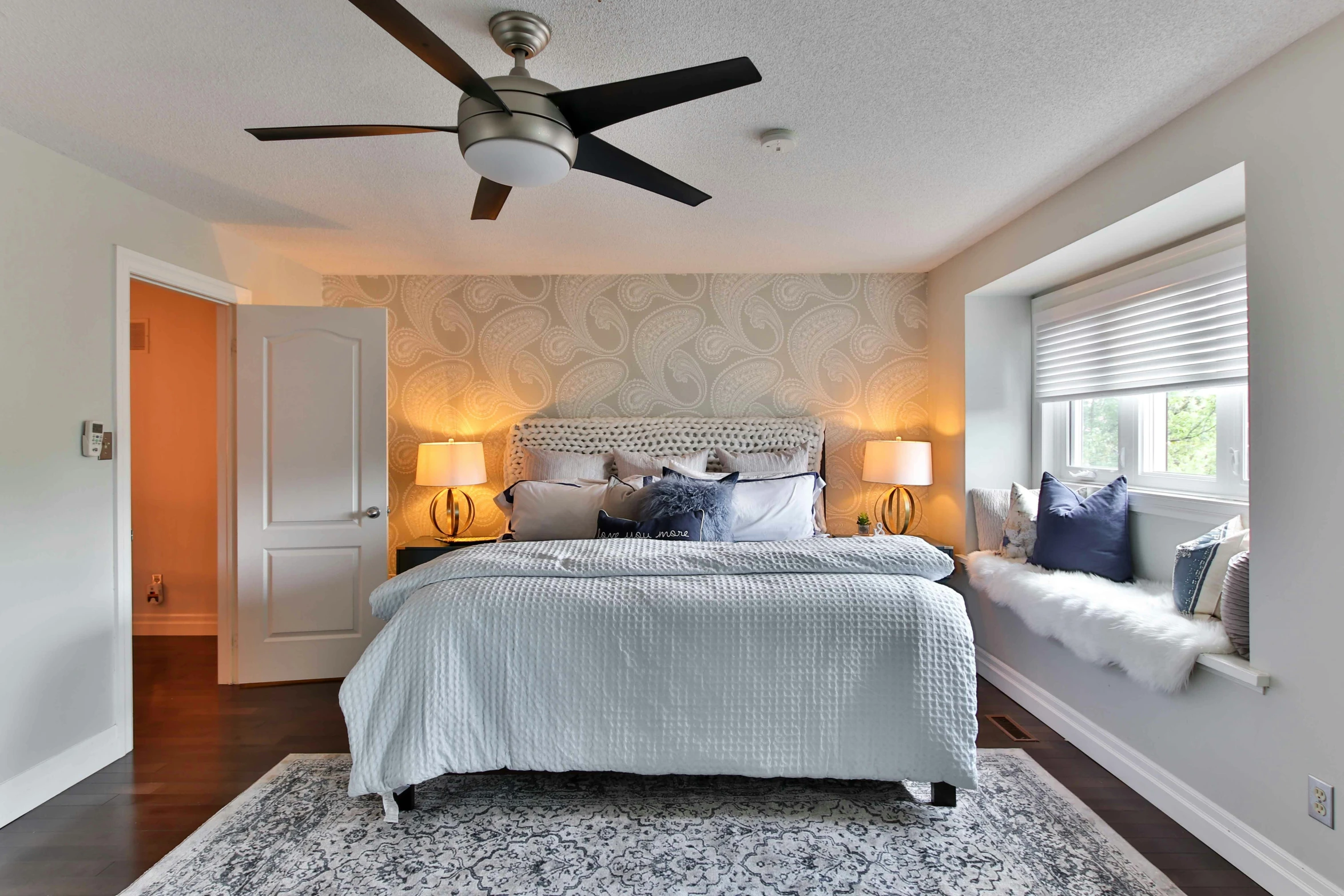 the bedroom has a large bed, mirror and ceiling fan