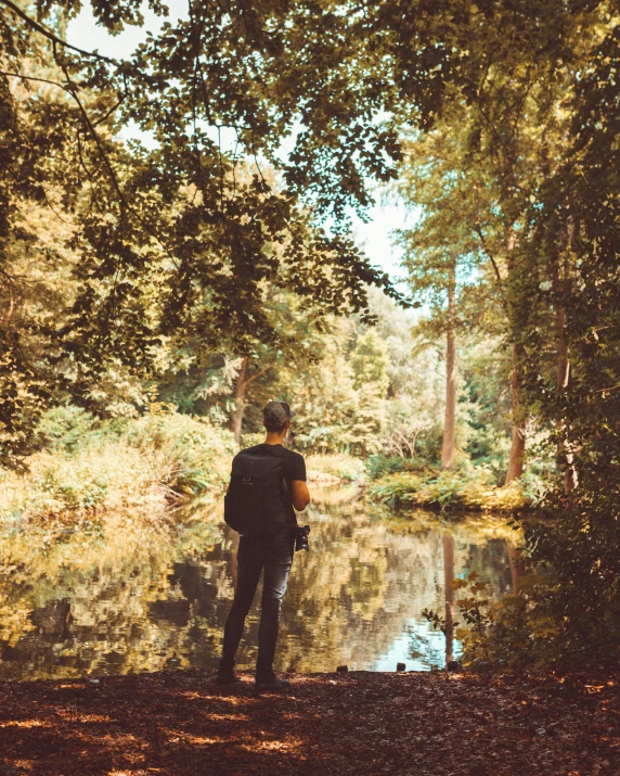 a man is standing by the water near trees