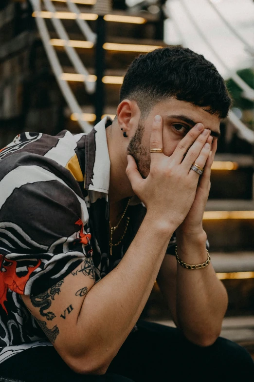 a young man is holding his face against his hands