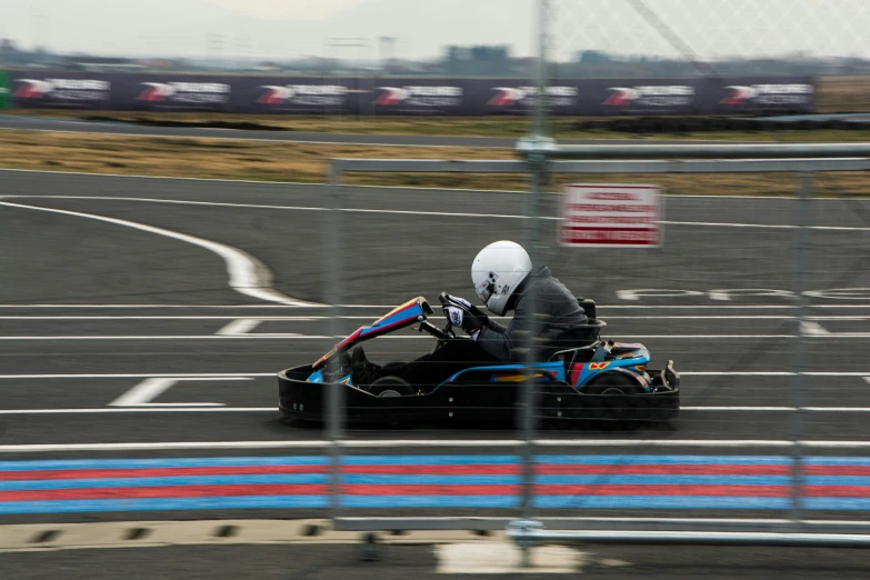 a man riding on a go kart on an asphalt race track