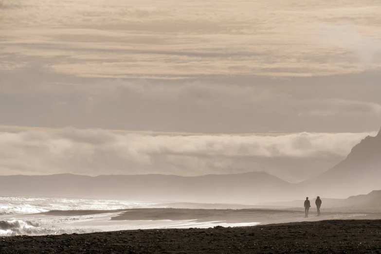 a couple walking on the beach in front of some ocean waves