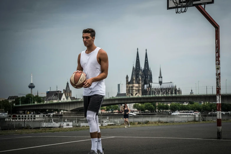 man standing with a basketball on court with castle in background