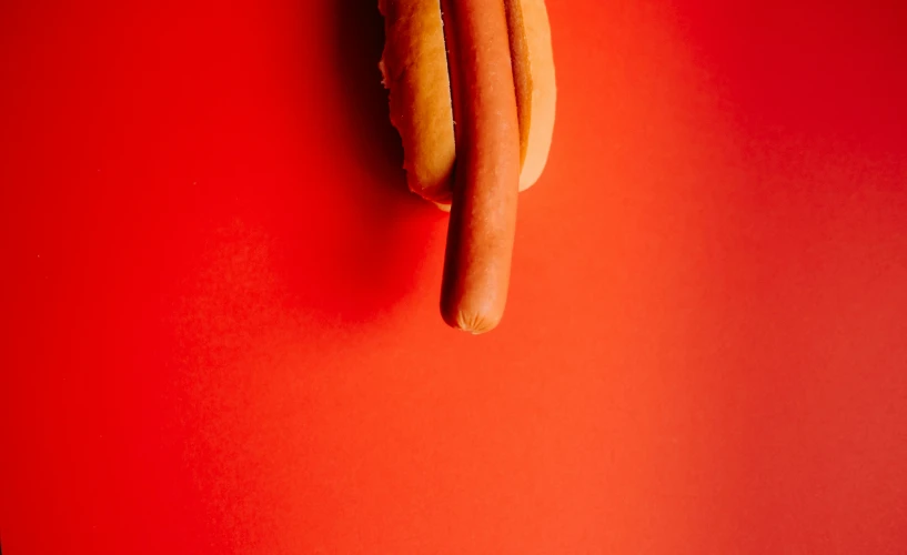 some mustard and dogs hanging from the side of a red table