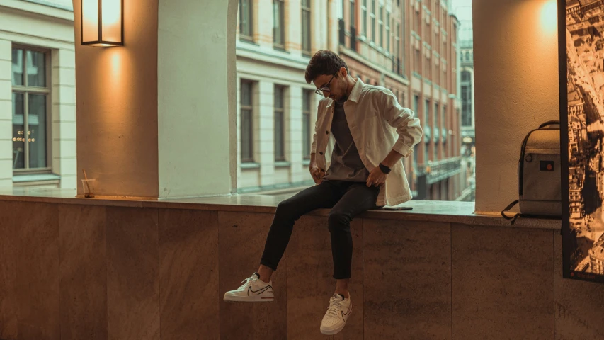 a man leaning against a wall with his shoes off