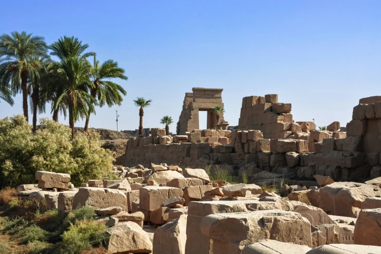 several stone ruins with palm trees and blue sky in background