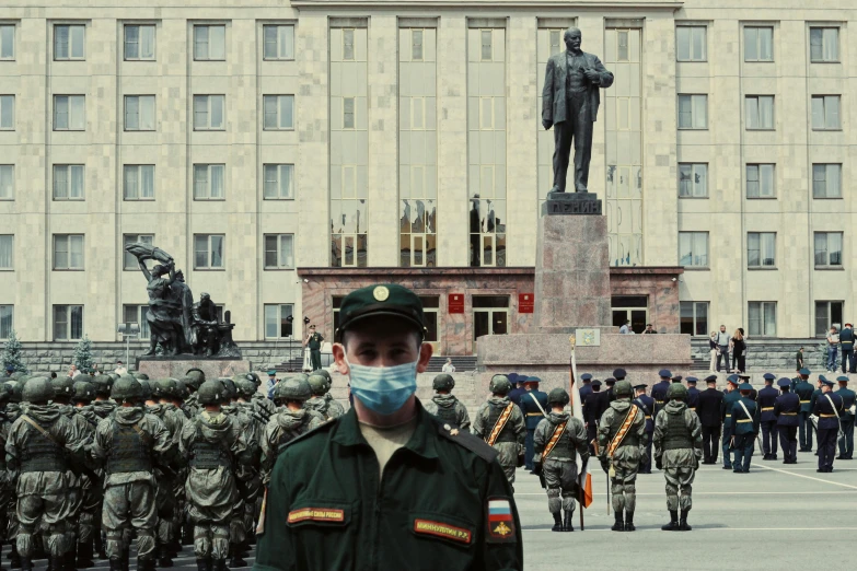 a man wearing a face mask in front of an army