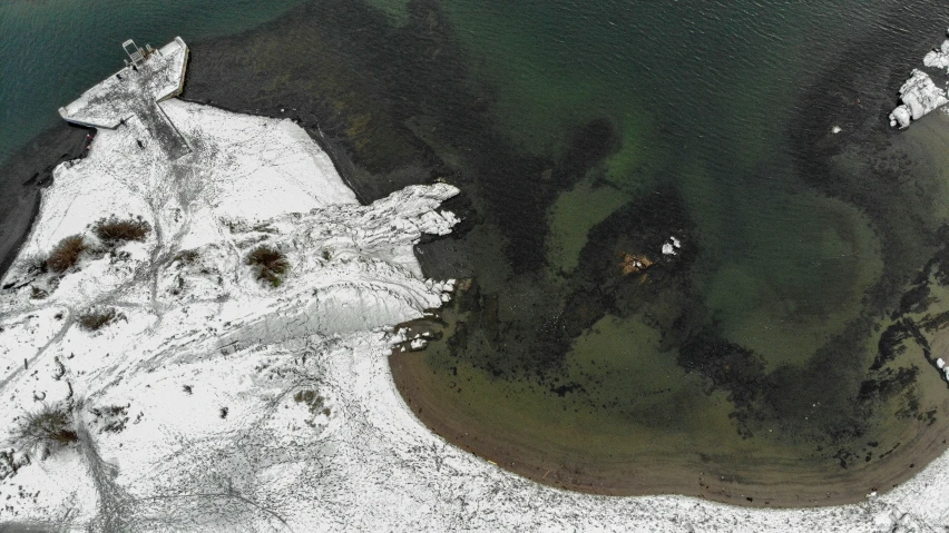 an aerial view of white snow covered hills and water