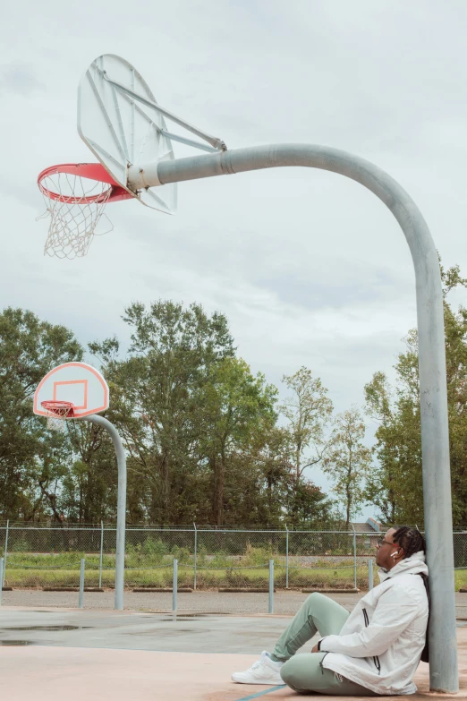 a man sitting underneath an over sized basketball hoop