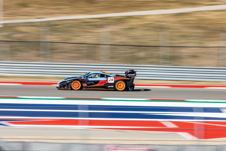 a black and orange sports car driving down the track