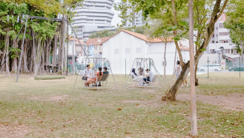 a group of people sitting on swings in a park