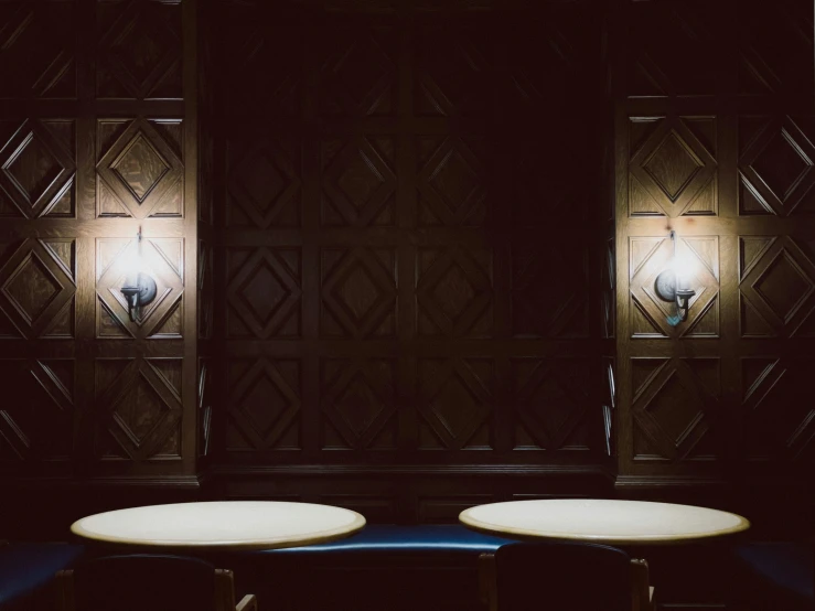 two white tables sitting in front of a wall light