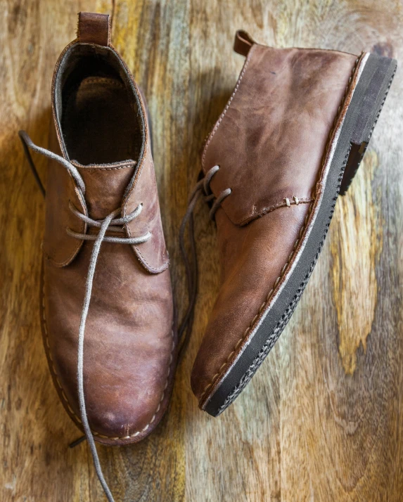 a pair of brown shoes is shown on a wooden table
