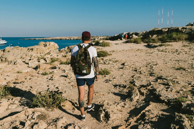 a man wearing a backpack stands on the beach