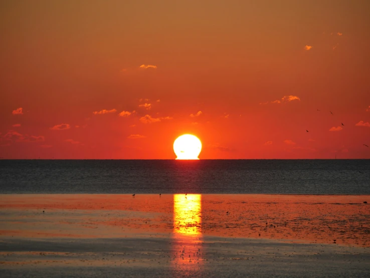 a large orange and yellow sun over the ocean