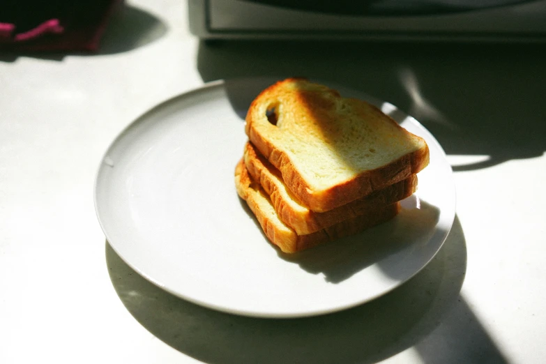 slices of sandwich on white plate next to a cup of coffee