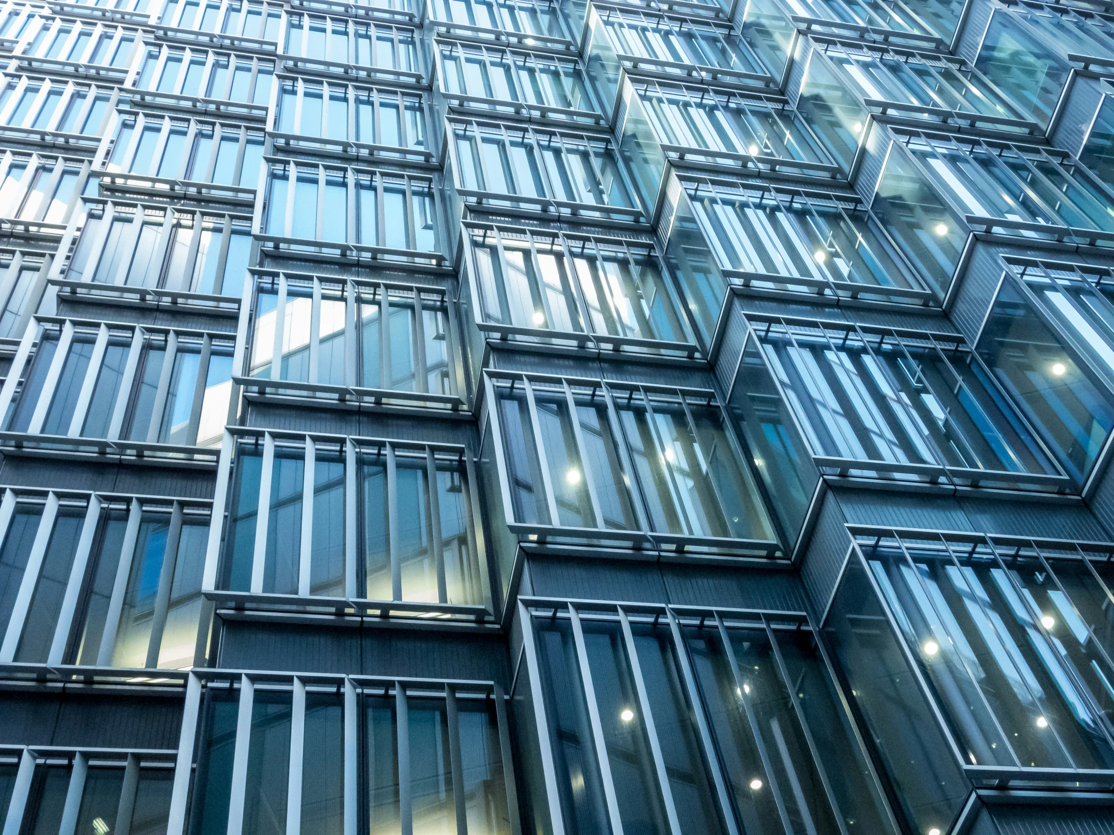 a large building has multiple windows that are reflecting the sky