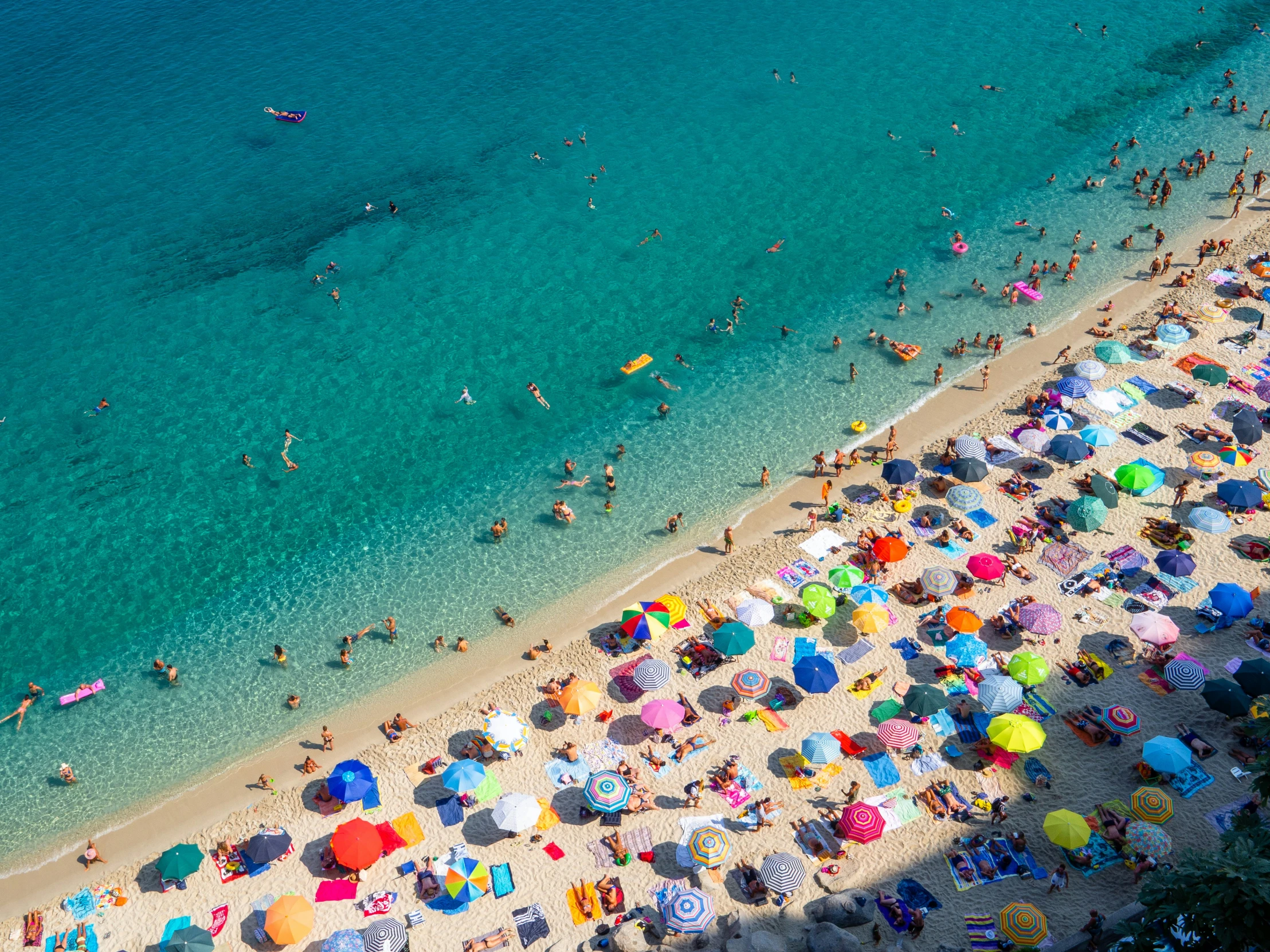 some people at the beach with umbrellas and swimming