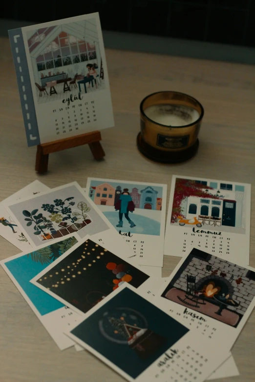 several blank calendars on the table with pictures and a candle