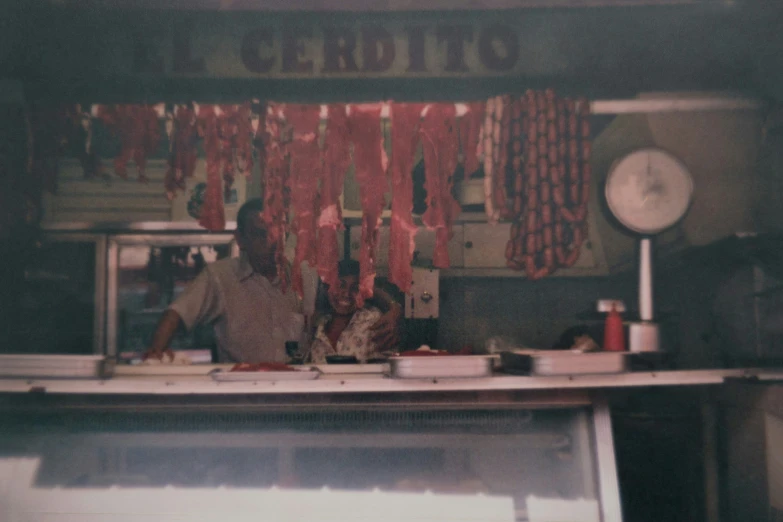 a butcher with meat hanging from a bar