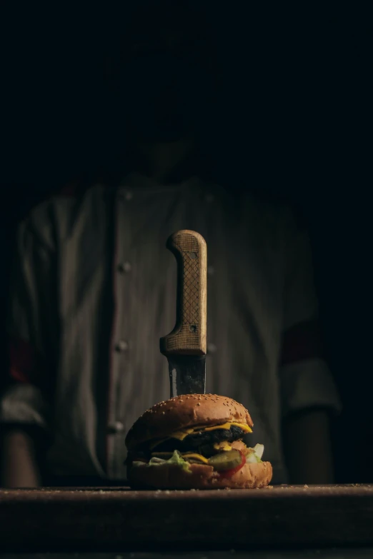 the man is standing behind a knife in front of a burger