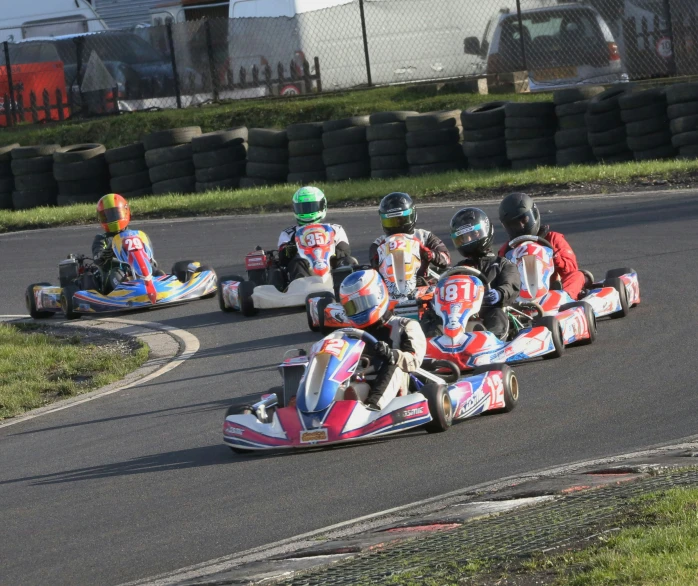 a number of go kart racing with racers on it