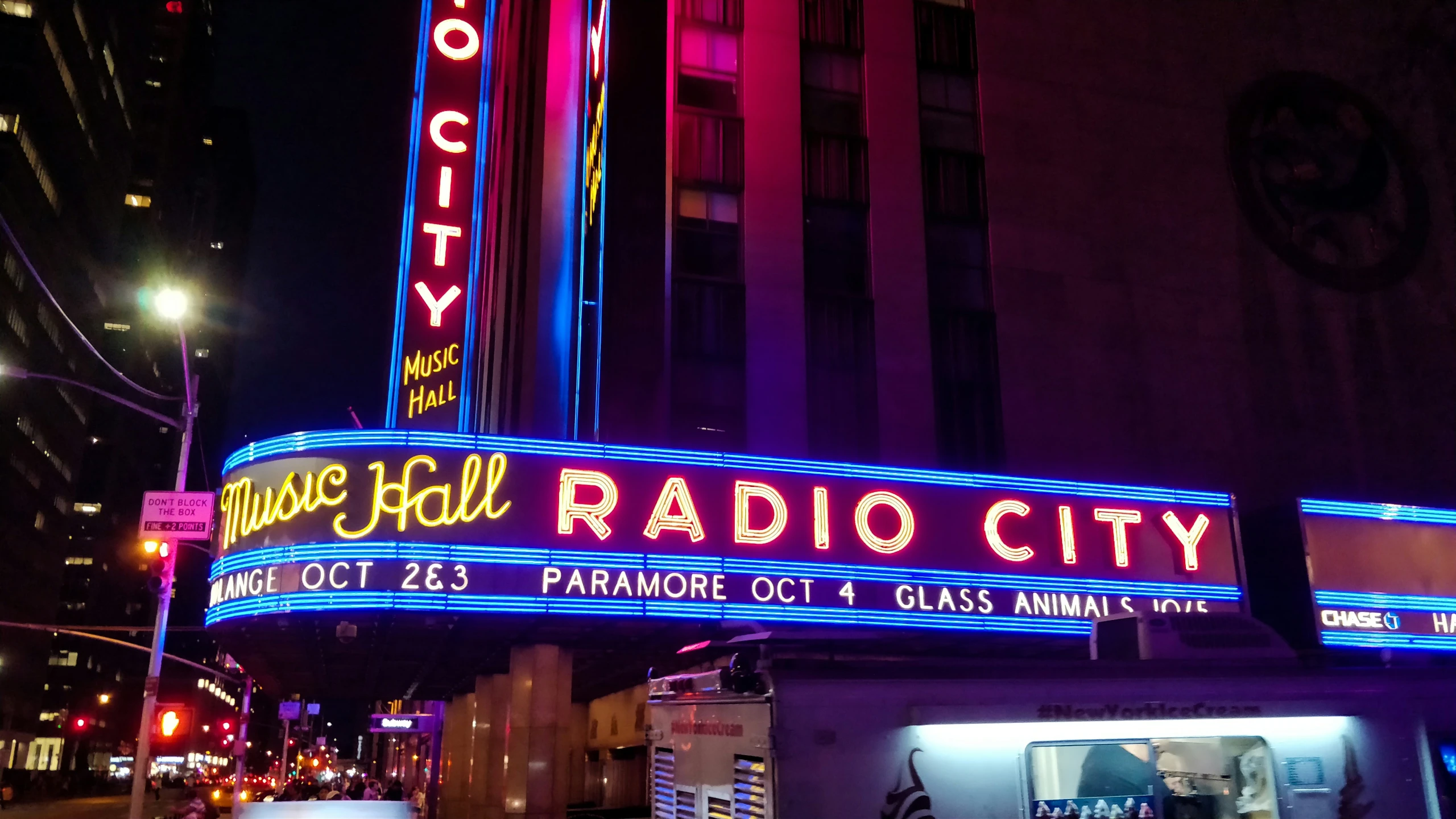 people walk in front of the radio city music hall in new york