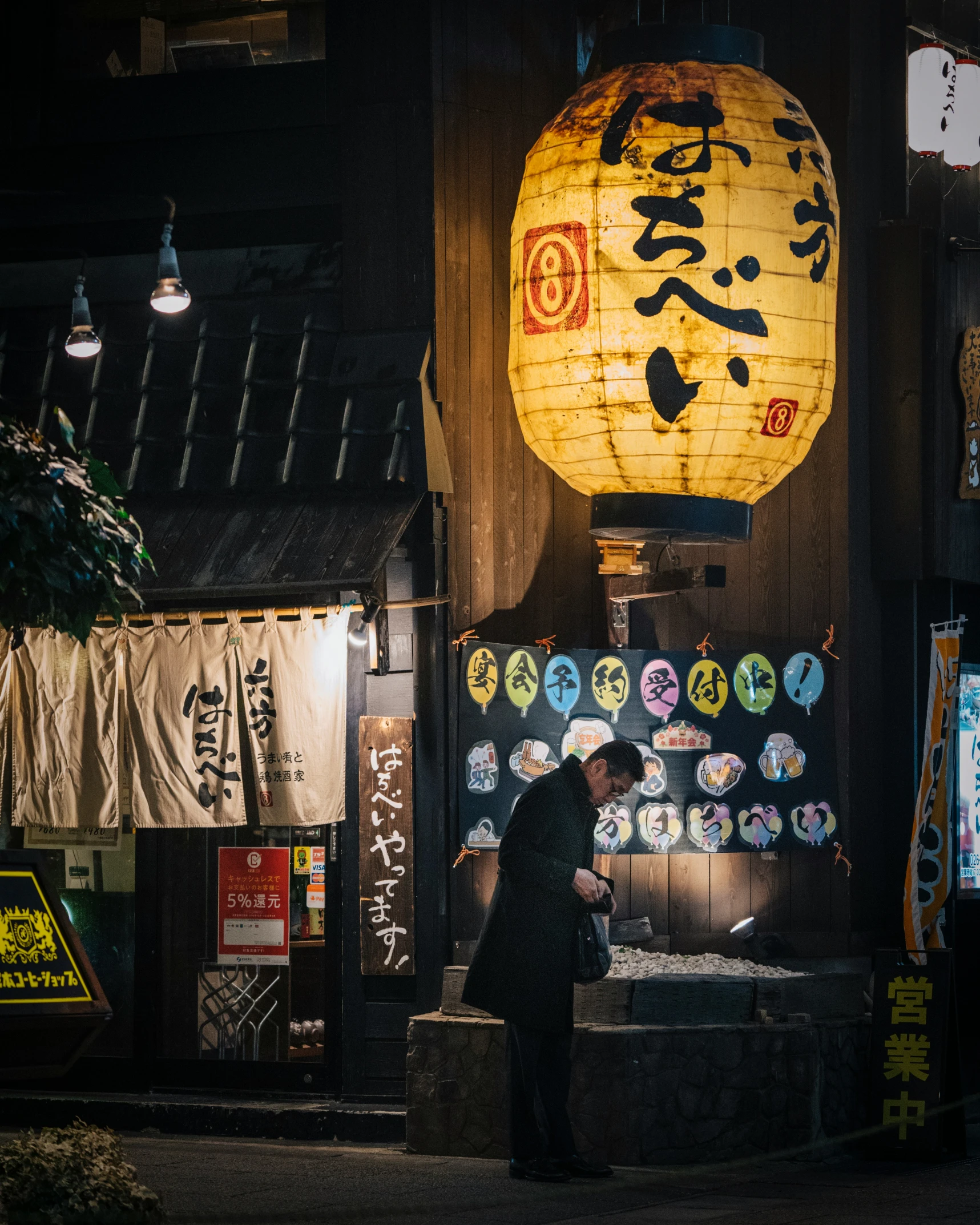 a man is standing outside by a lighted lantern