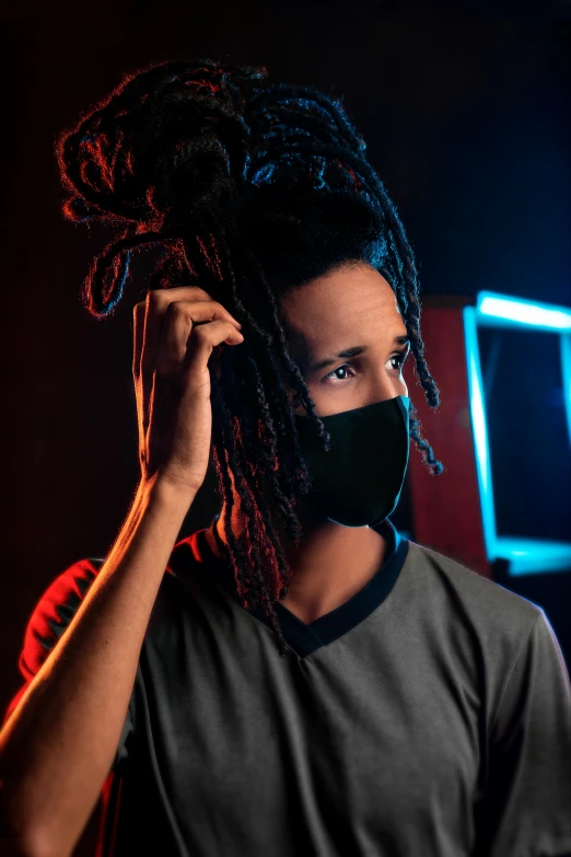 a young man with dreadlocks wearing a face mask