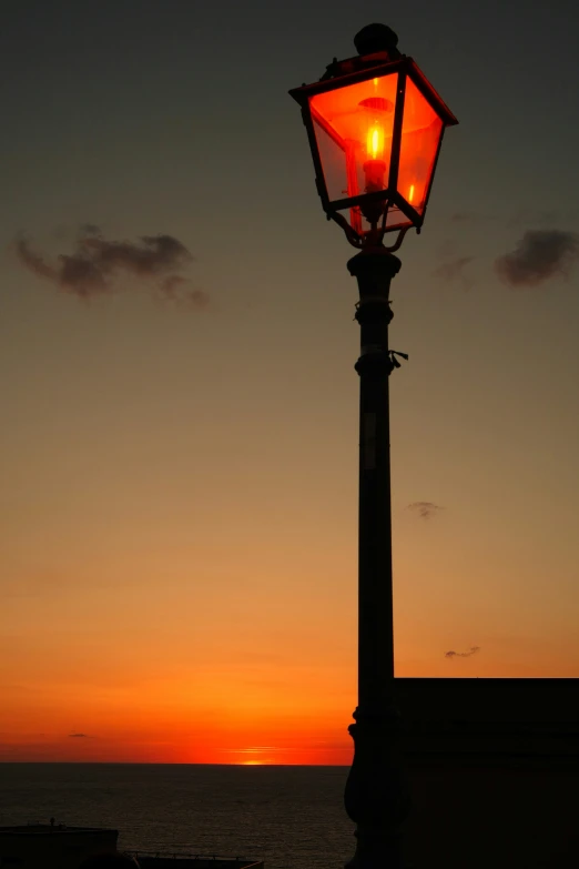 a light post with the sun setting on the horizon