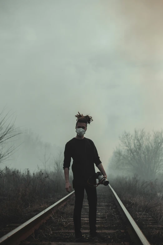 a man standing on the railroad tracks with a mask
