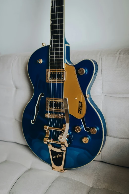 an old blue guitar hanging from the back of a couch