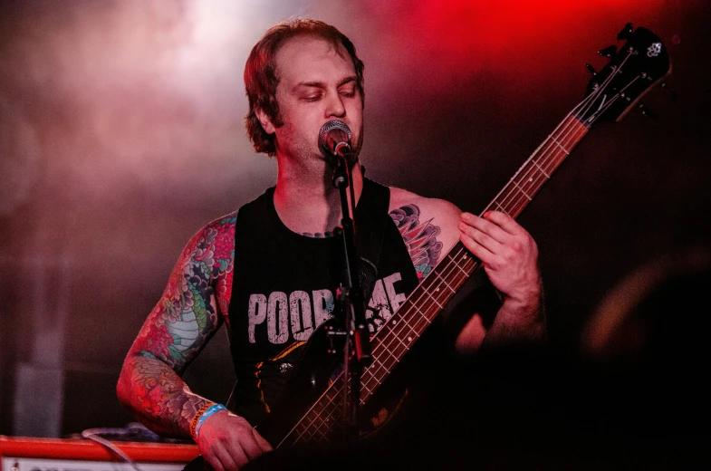 man on stage playing an electric bass guitar
