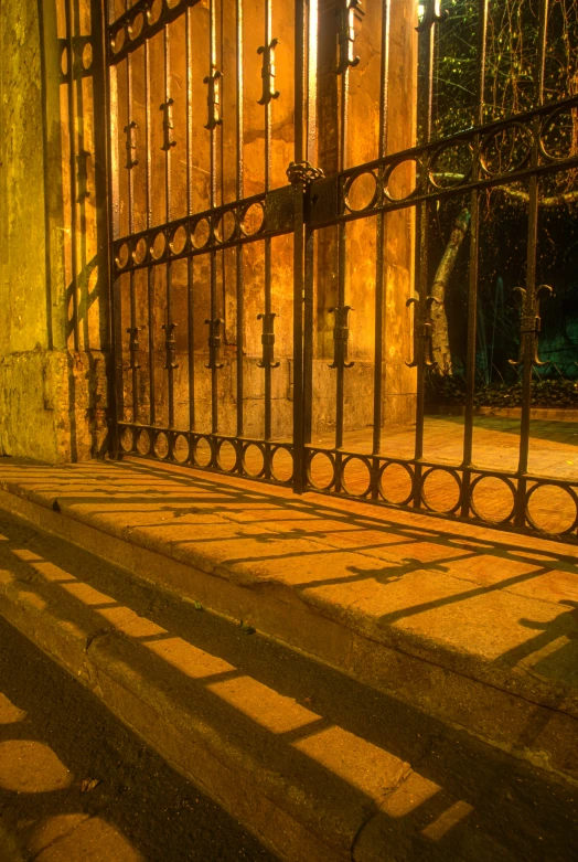 shadow is cast on the ground next to a gate