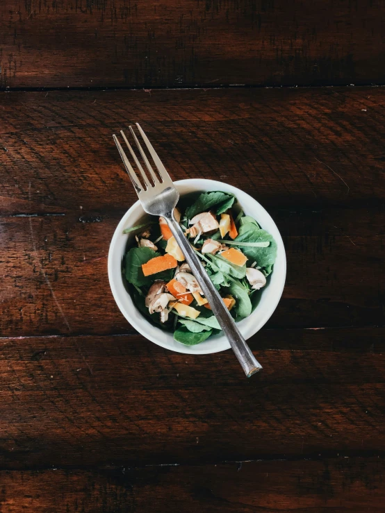 a white bowl filled with meat, vegetables and forks