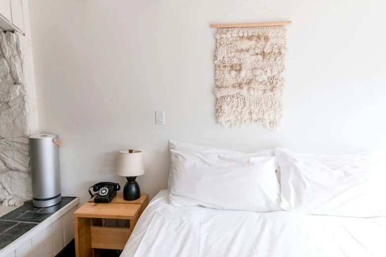 a bed with white blankets and a white pillow and nightstand