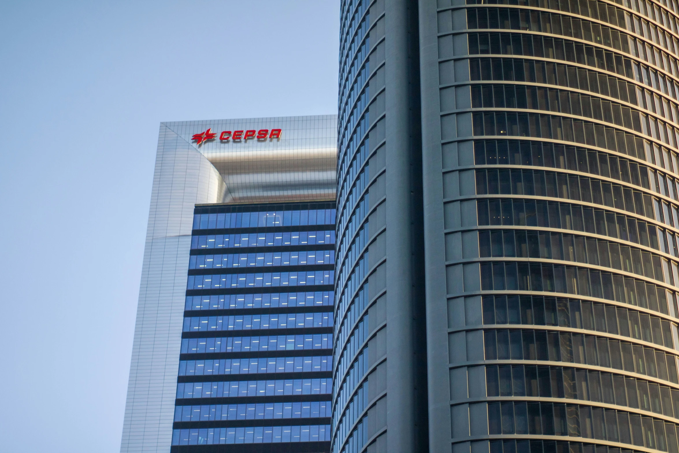 two large buildings next to each other in front of blue sky