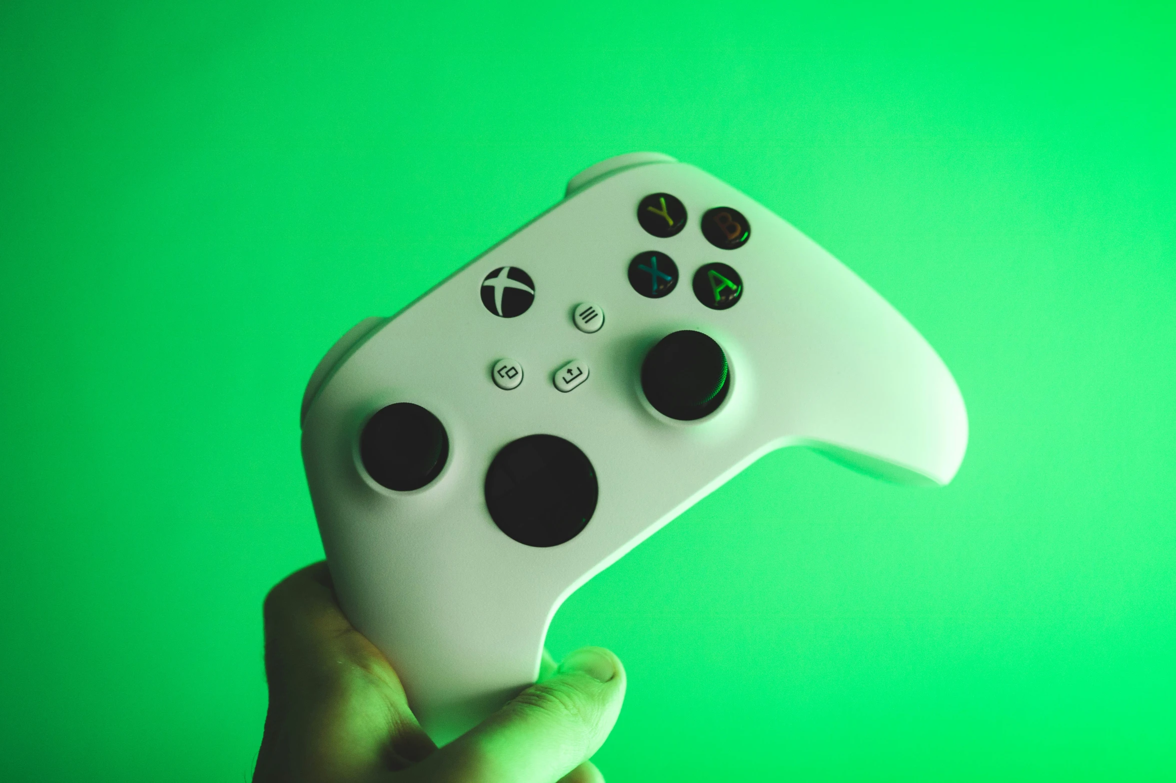 a person holding up a controller in front of a green wall