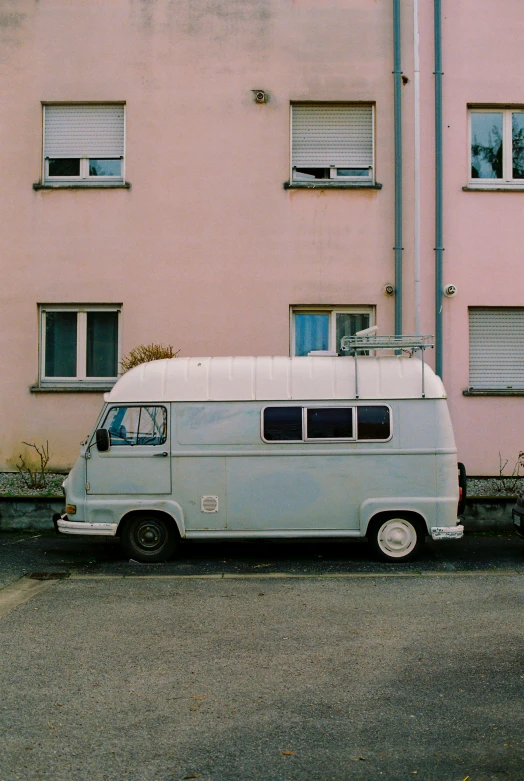 a white bus is parked next to a pink building