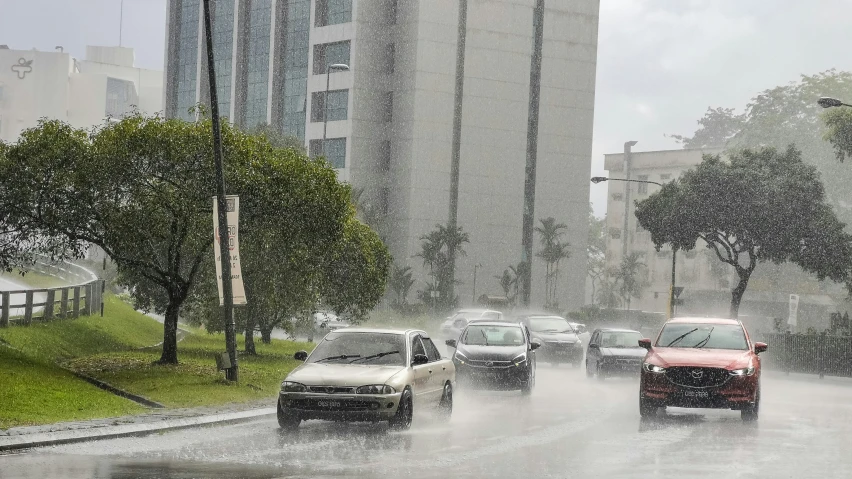 a couple of cars traveling down a rainy street