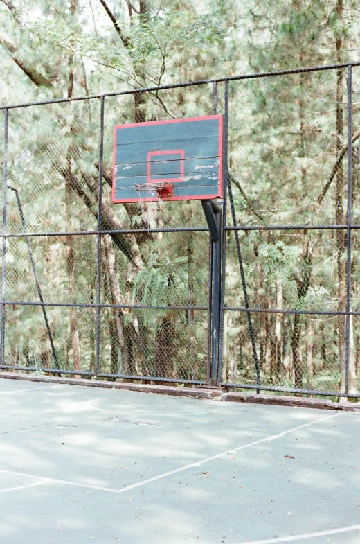there is a basketball hoop and a basketball board in front of a fence